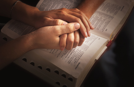 Fotolia 124164722 XS.jpg praying hands over Bible